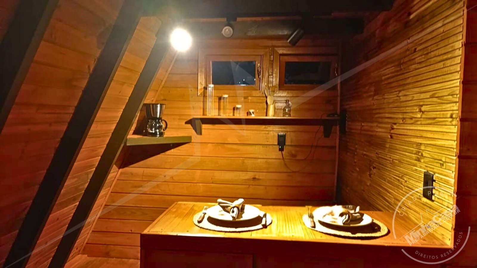 Cozinha do A‑Frame 1 (51,77 m²) – Iluminação Noturna Interna Cozinha sem móveis do chalé A‑Frame 1 fotografada à noite, com estrutura em pinus tratado