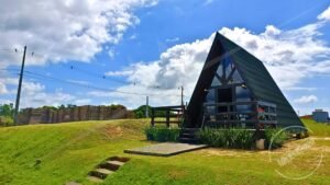 Fachada frontal do chalé A‑Frame 1 em pinus autoclave, capturada de distância média