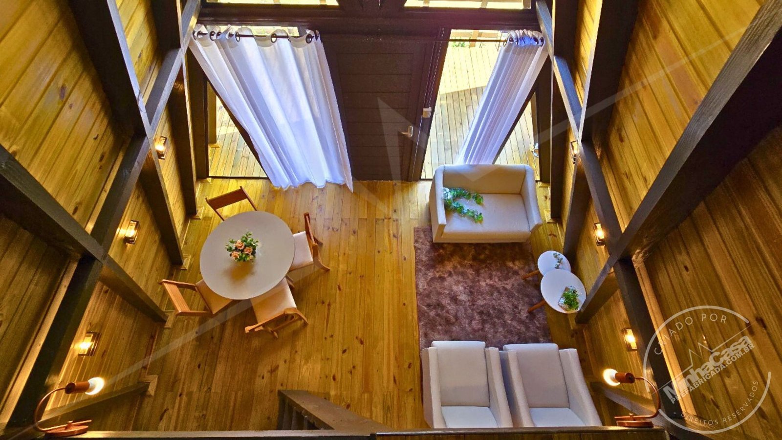 Vista do Mezanino para a Sala – A‑Frame 1 (51,77 m²) Perspectiva do mezanino olhando para baixo, mostrando sala e escada do chalé A‑Frame 1